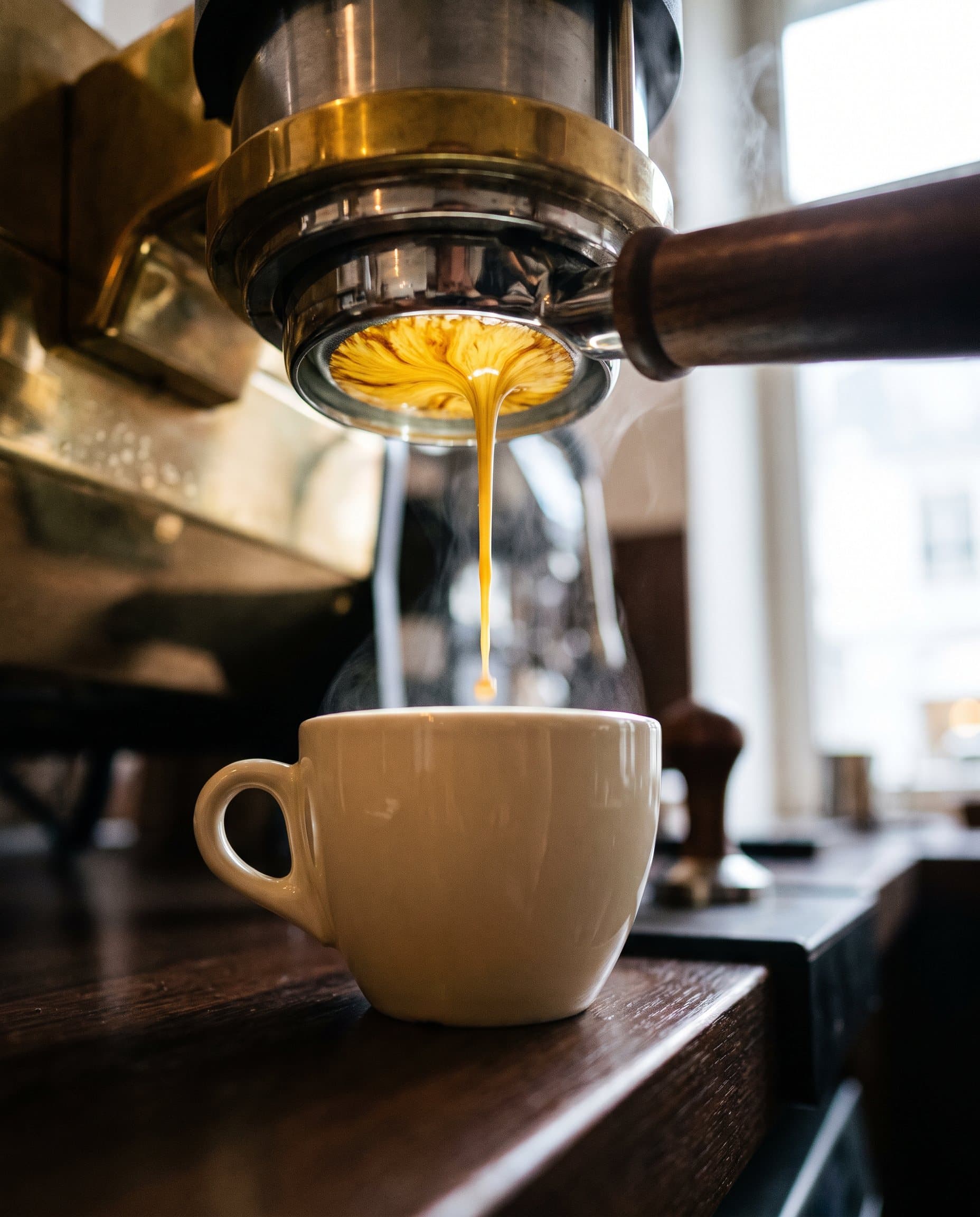 Espresso fliesst aus dem Siebträger in eine Tasse